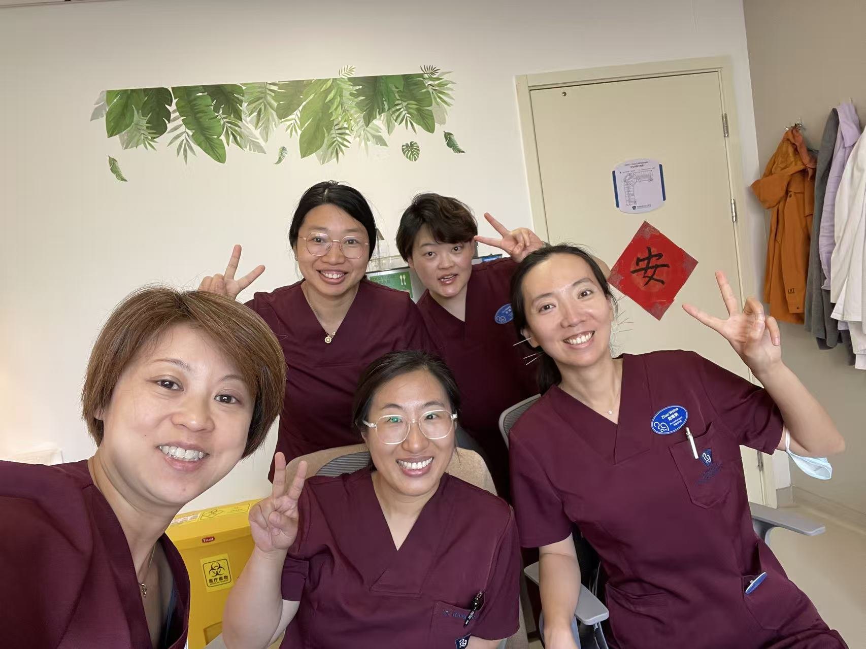 Dr Deb with colleagues in maroon scrubs, smiling for a selfie at Beijing United Family Hospital