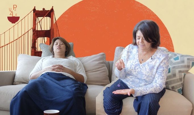 Two women on a couch, one reclined with her eyes closed, with a Golden Gate Bridge motif