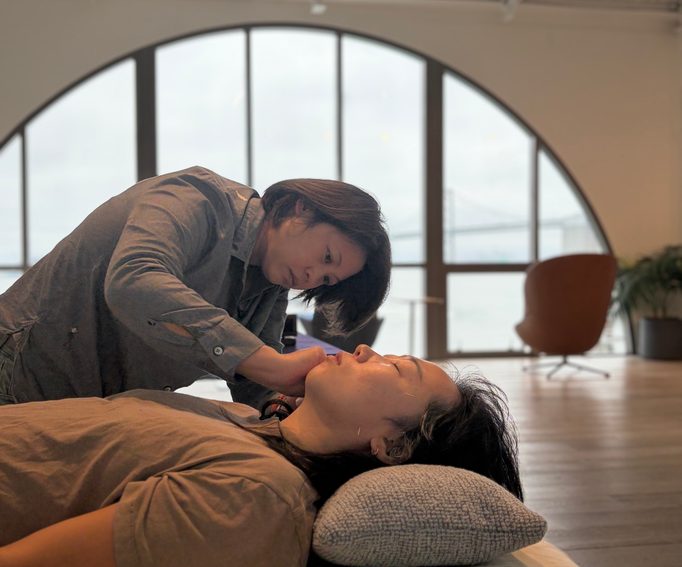 Dr. Deb checks a patient's jaw during cheek acupuncture, with fine needles on the patient's face