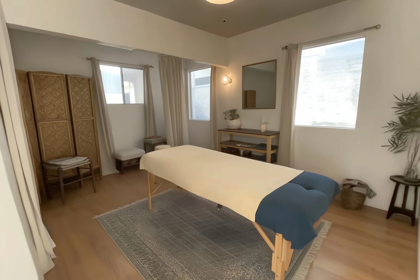 A private treatment room with a massage table, folding screen, and mirror