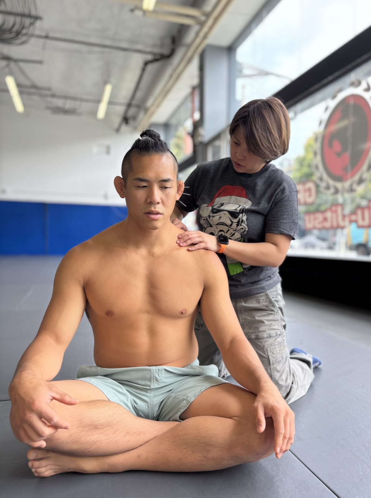 Dr Deb treating a patient’s shoulder at a jiu-jitsu gym