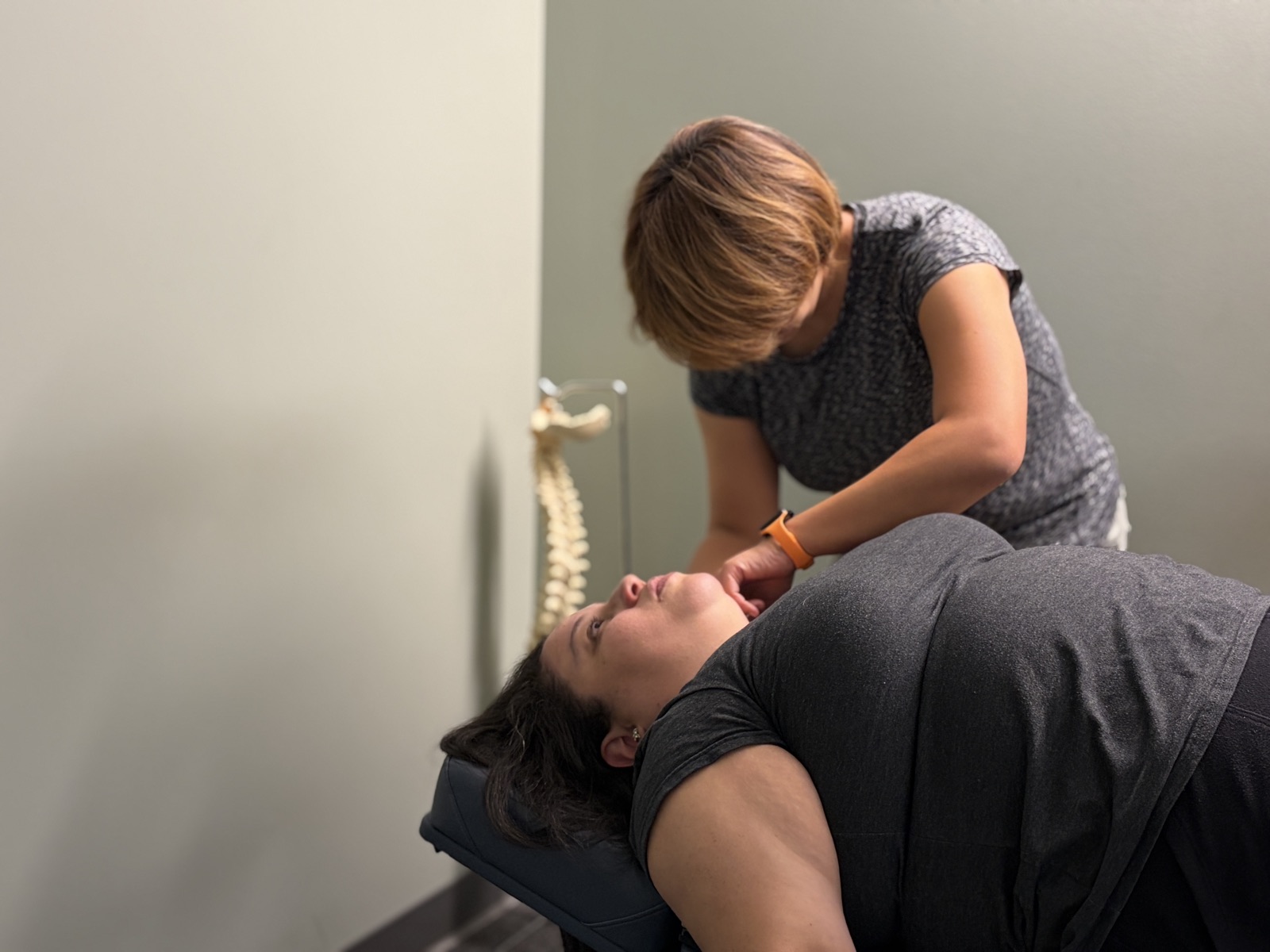 Dr Deb Ma treating a patient with a spine model in the background